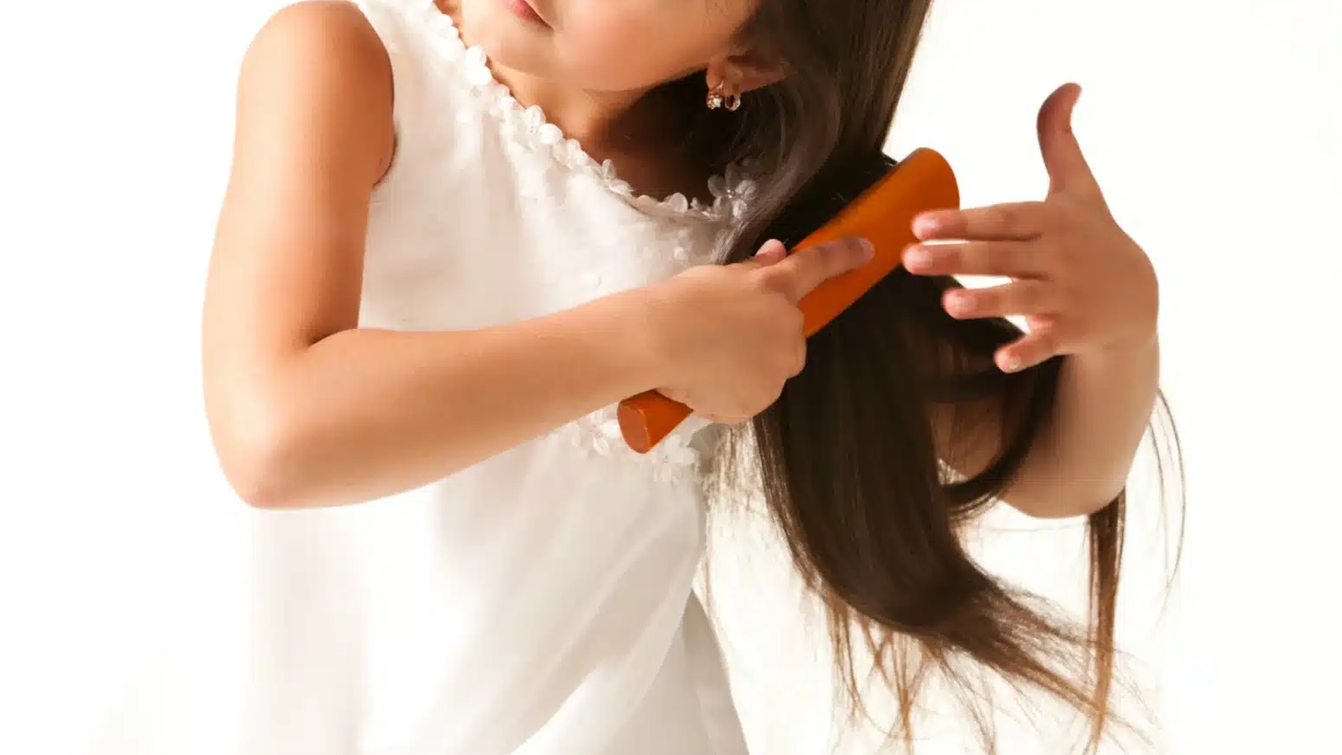 Close-up of a child running a fine-toothed comb through long brown hair to inspect for nits