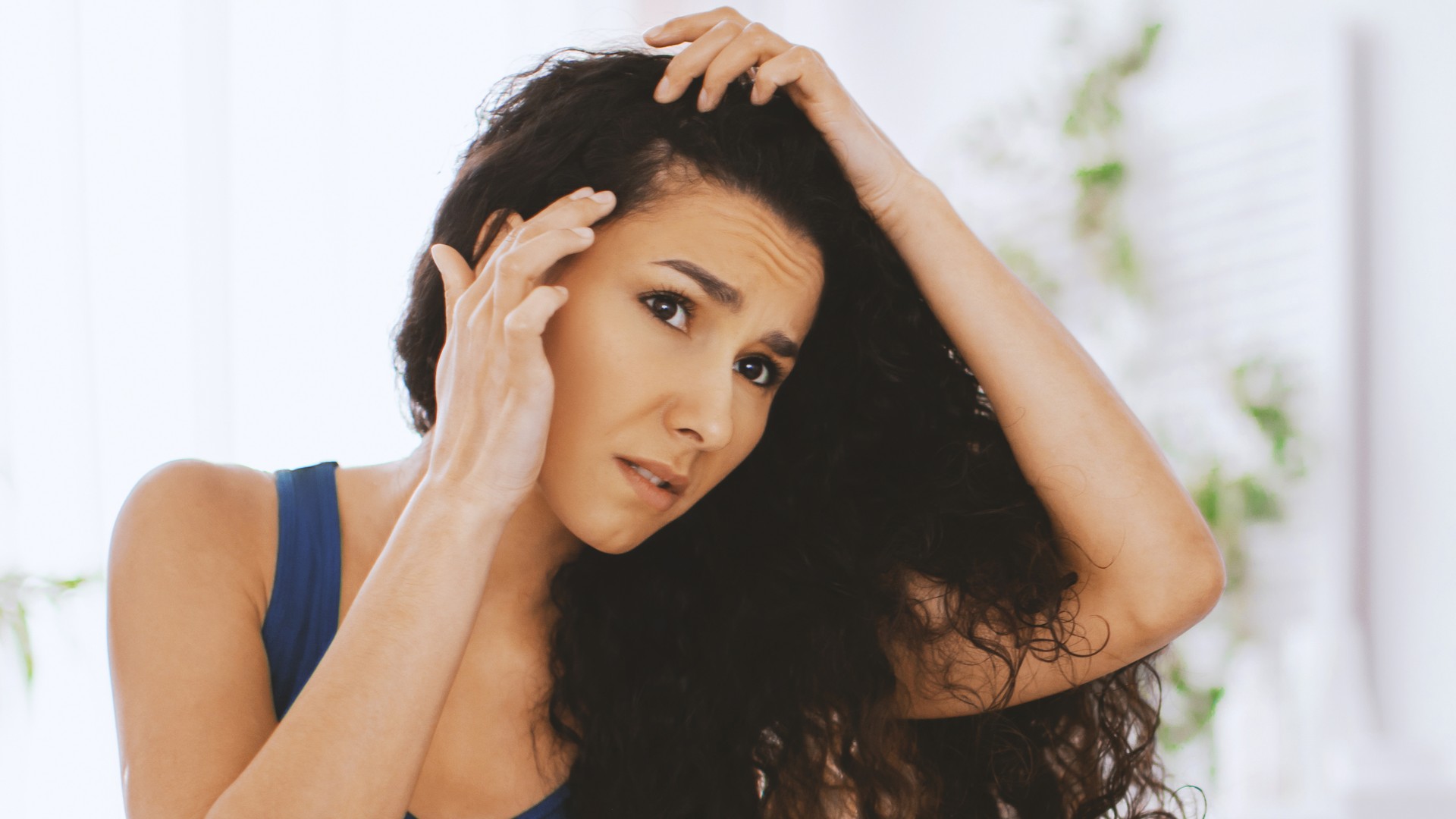 Adult woman parting her hair to inspect an itchy scalp for signs of head lice