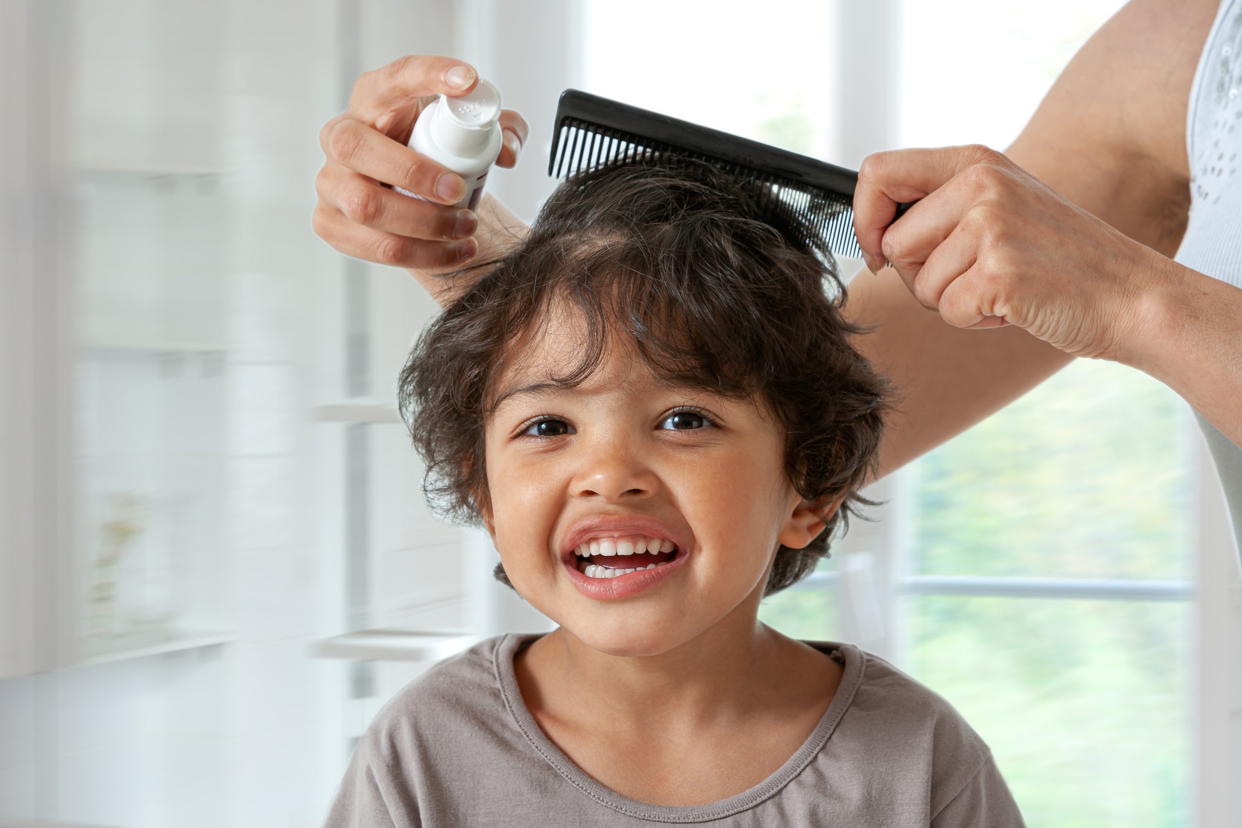 Mother treating daughter hair against lice. Head lice treatment for schoolchild.