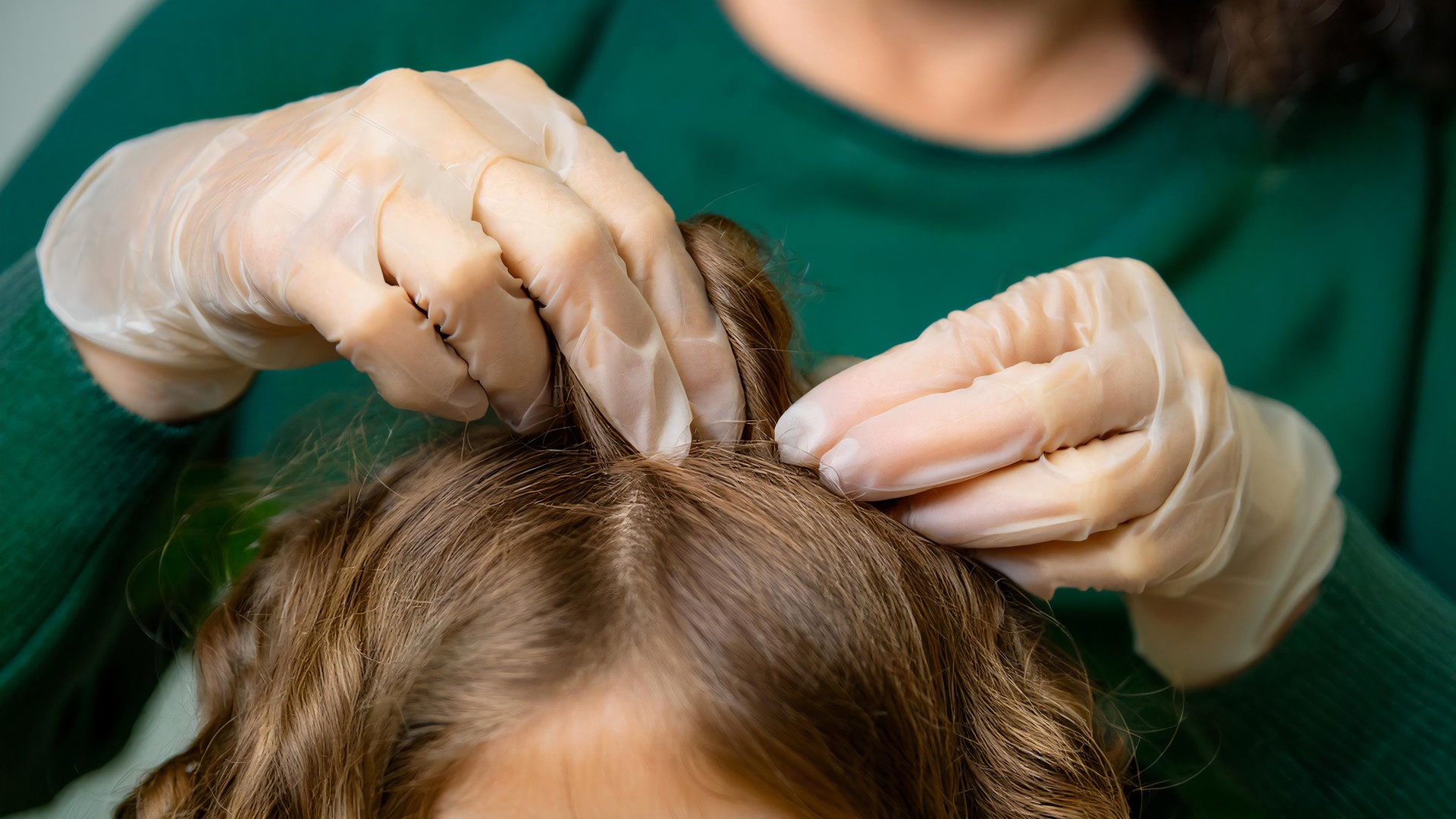 Professional checking a child scalp while discussing head lice across different hair types