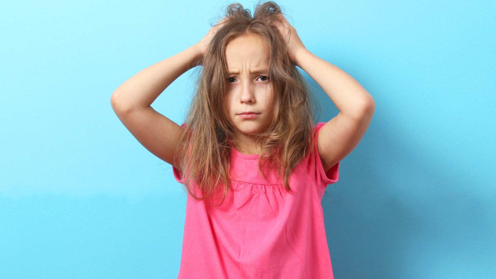 Child scratching her head while a parent considers common head lice myths