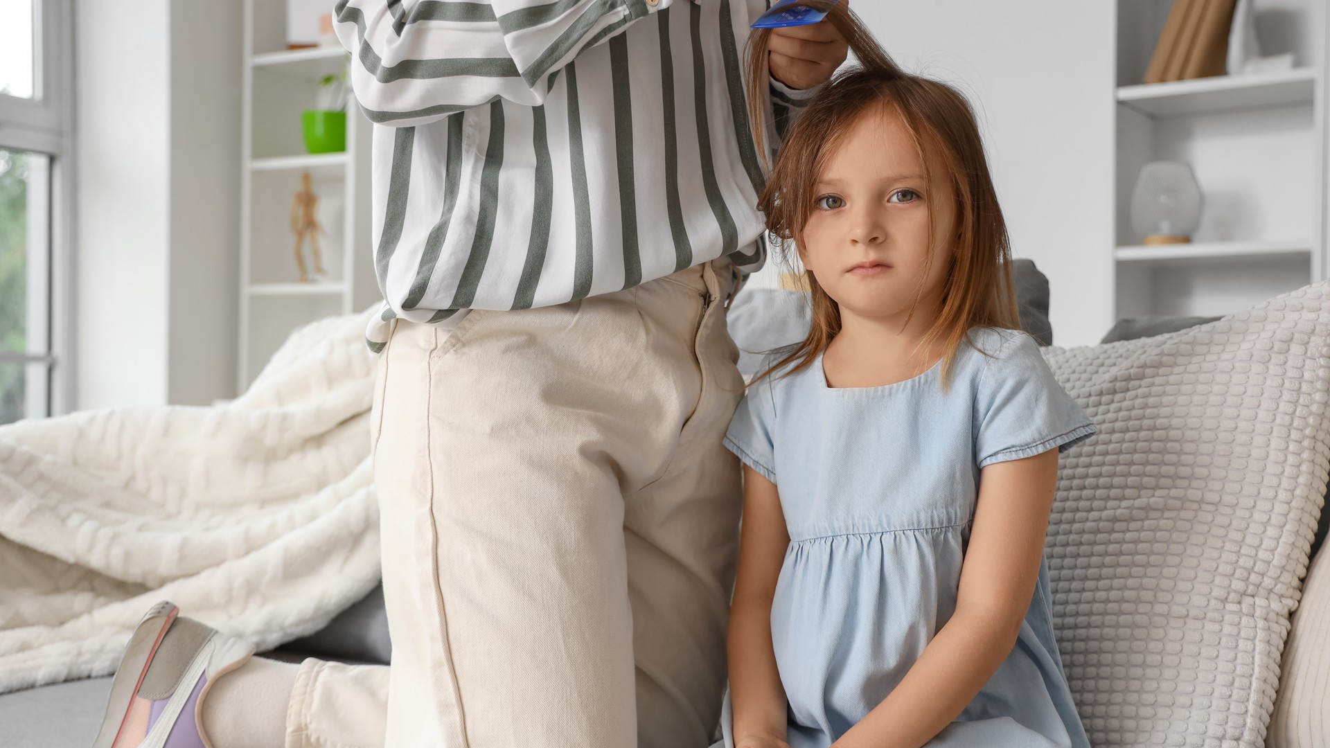 Mother checking a child's hair with a magnifying glass and lice comb at home