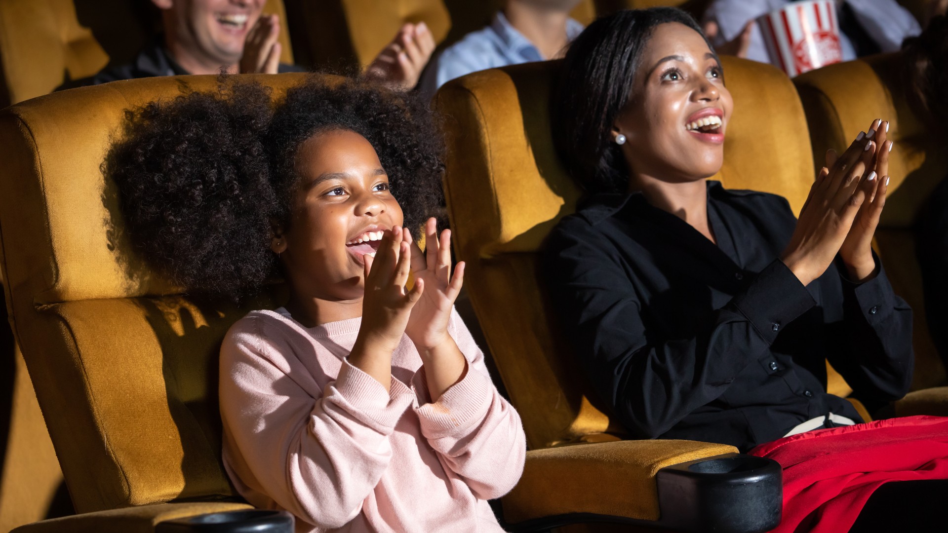 Family seated together in a movie theater while considering head lice risks in public places