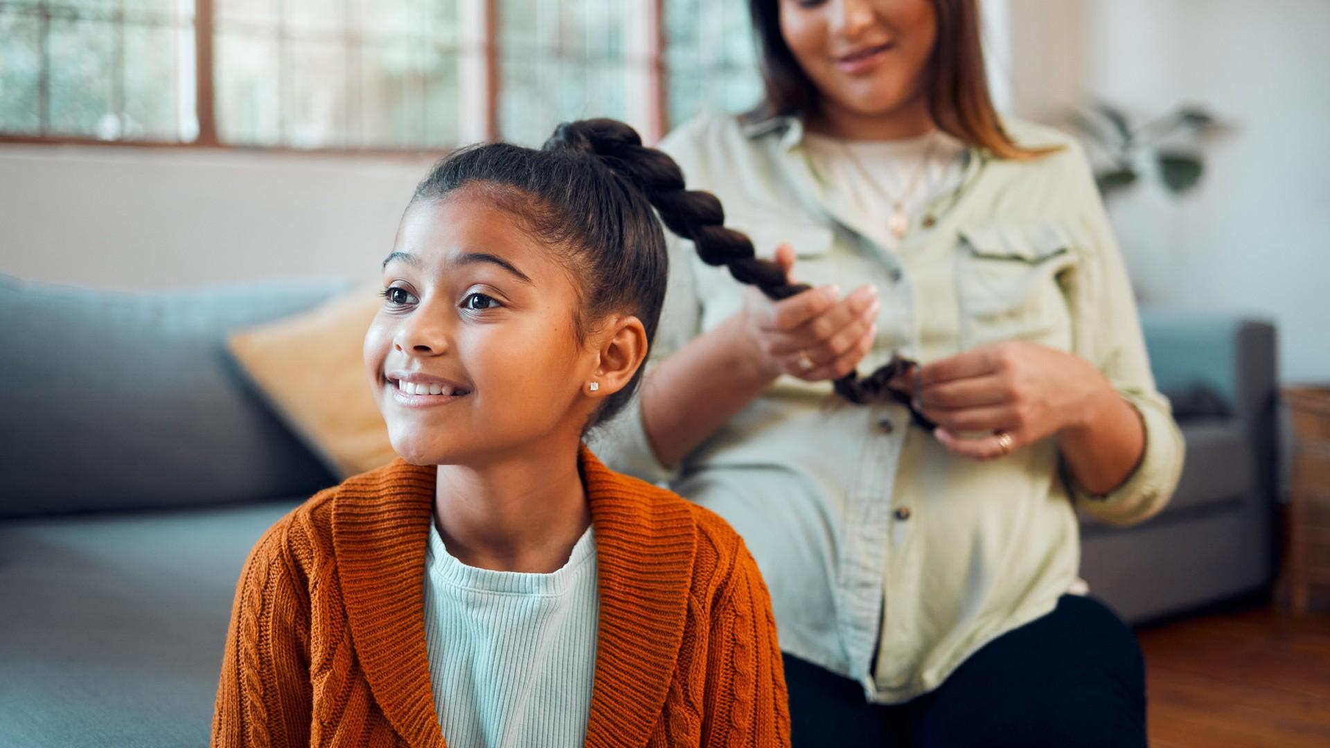 Parent braiding a child's hair as a head lice prevention step after exposure